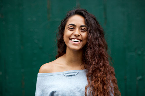 Image Text: 500x332_0003_front portrait of happy young Indian woman laughing against green background