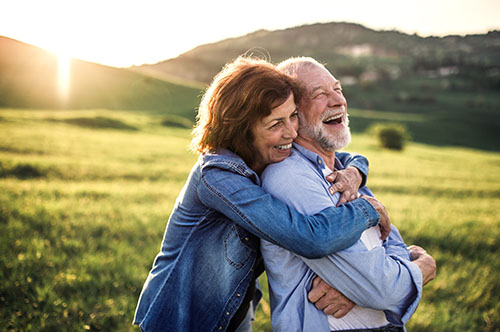 Image Text: 500x332_0011_Side view of senior couple hugging outside in spring nature at sunset.